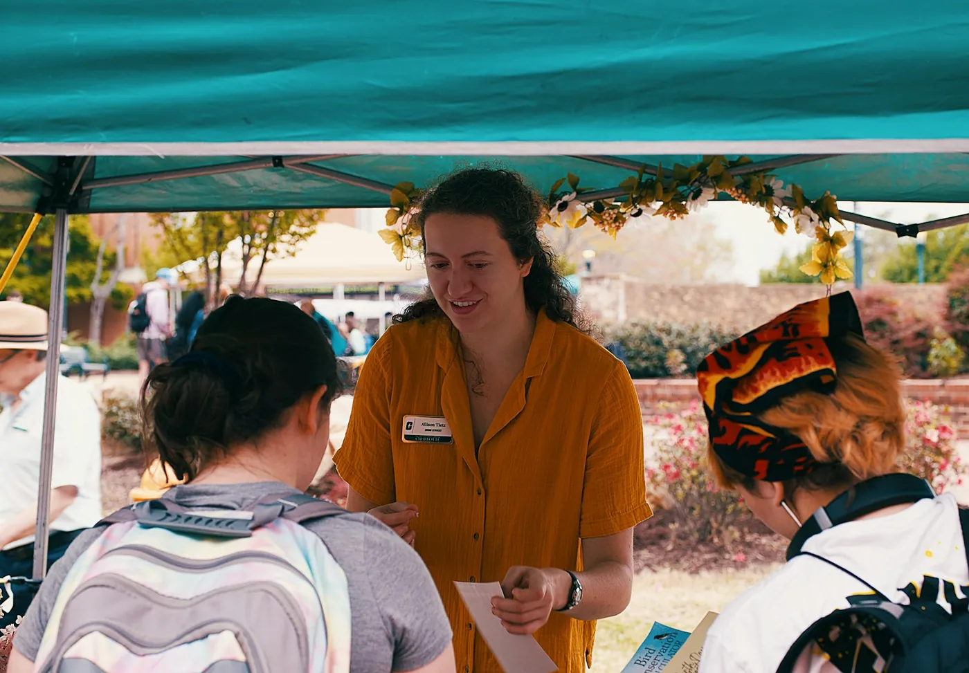 A volunteer at an outdoor event tent helping people find their way
