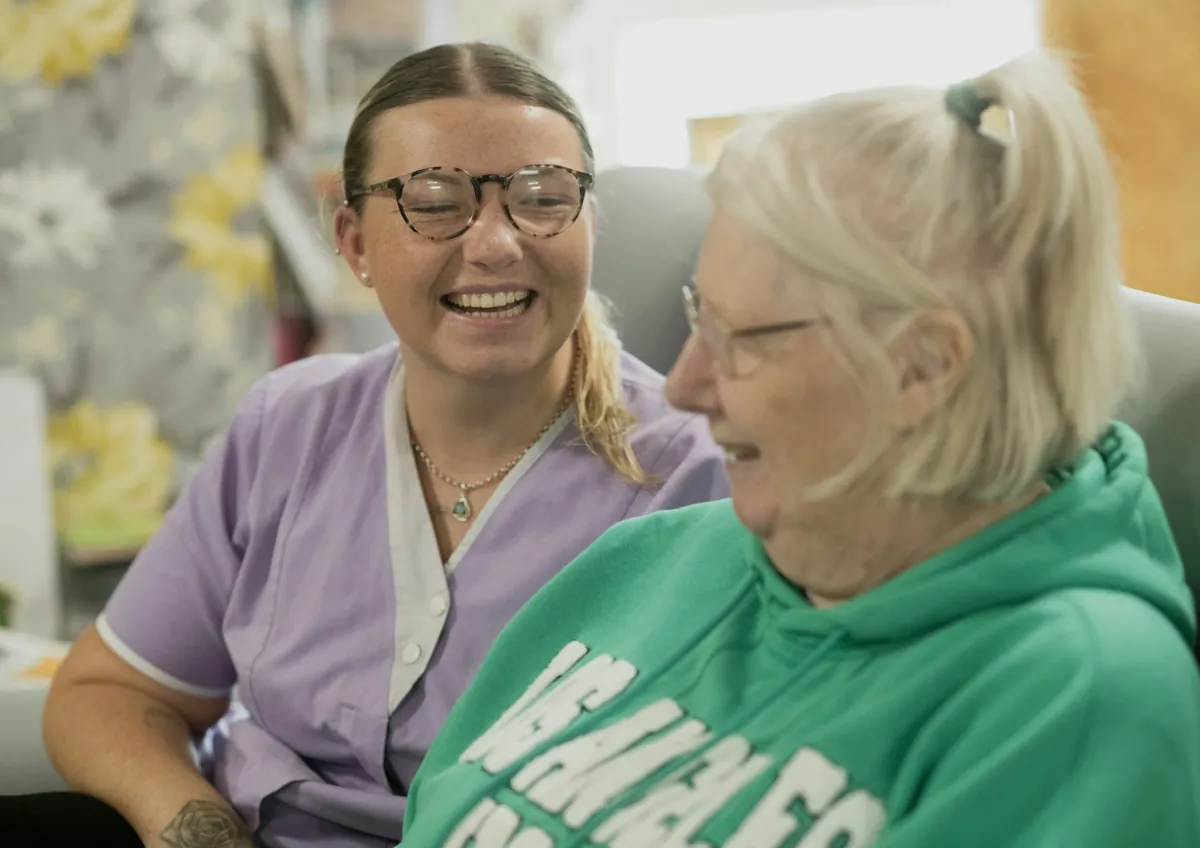 A volunteer laughing with an elderly woman during a visit